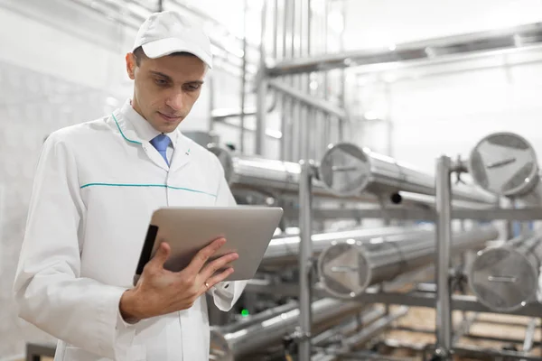 Τεχνολόγος με ένα tablet με τα χέρια του στο εργοστάσιο γαλακτοκομικών προϊόντων — Φωτογραφία Αρχείου