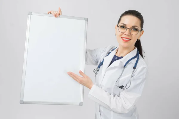 Porträt einer Frau mit Brille im weißen Gewand mit Magnettafel in den Händen isoliert auf weißem Hintergrund — Stockfoto