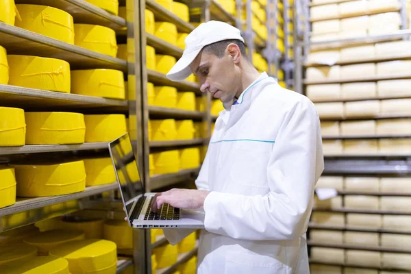 Trabajador con un portátil en sus manos en el almacén de queso —  Fotos de Stock