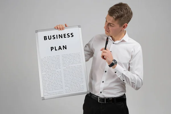 Молодий чоловік тримає бізнес-план і ручку ізольовано на світлому фоні — стокове фото