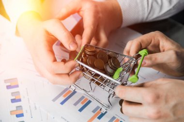 Mens el mankeni alışveriş sepeti madeni paralarla dolu farklı yönlere çekti
