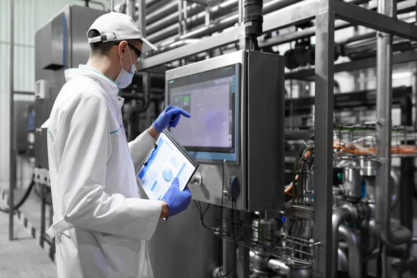 Technologe macht sich Notizen, während er in der Produktionsabteilung der Milchfabrik steht — Stockfoto