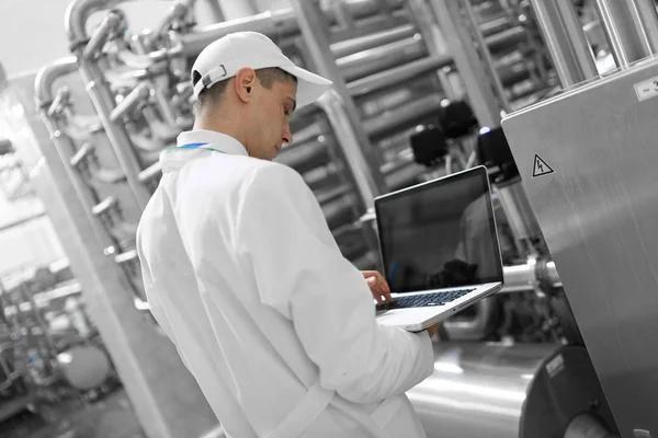 Technologue avec un ordinateur portable dans ses mains à l'usine laitière — Photo