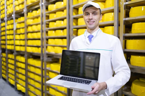 Werknemer toont een leeg scherm laptop in voorraad kaas — Stockfoto