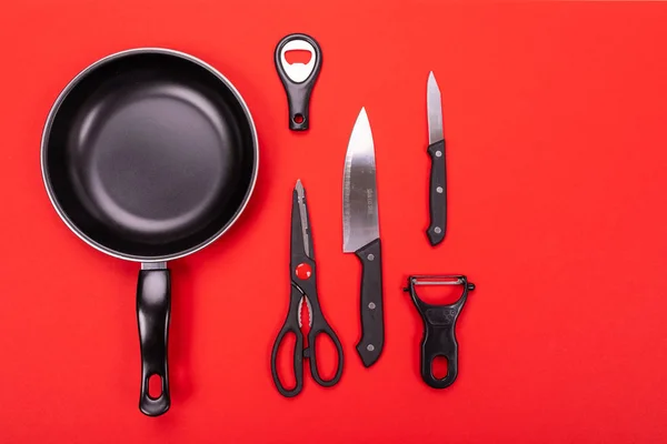 Frying pan with kitchen utensils isolated on red background — Stock Image Frying pan with kitchen utensils isolated on red background Stock Image
