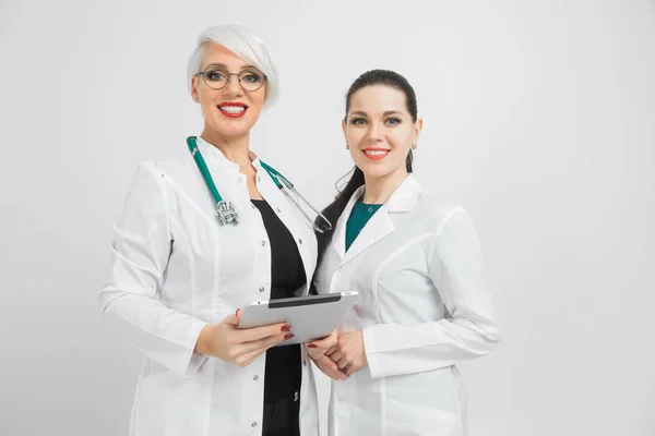 Duas médicas com tablet e lençol com análise em mãos isoladas sobre fundo branco — Fotografia de Stock