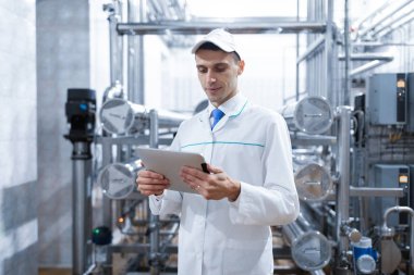 beyaz bir elbise içinde onun elinde bir tablet fabrikada üretim dükkanda adam