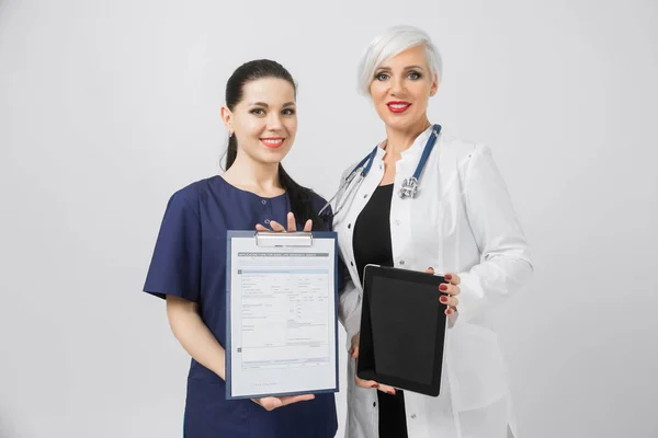 Duas médicas com tablet e lençol com análise em mãos isoladas sobre fundo branco — Fotografia de Stock