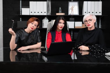 Ofis dizüstü bilgisayar ile masada oturan üç kadın meslektaşları