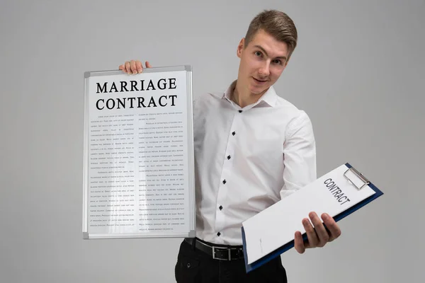 Junger Mann hält Plakat mit Ehevertrag und Vertrag isoliert auf hellem Hintergrund — Stockfoto