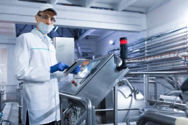 Dijital ekran süt fabrikasında yakındaki bir tablet ile teknoloji uzmanı duruyor