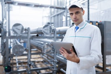 Süt fabrikasında onun elinde bir tablet ile teknoloji uzmanı