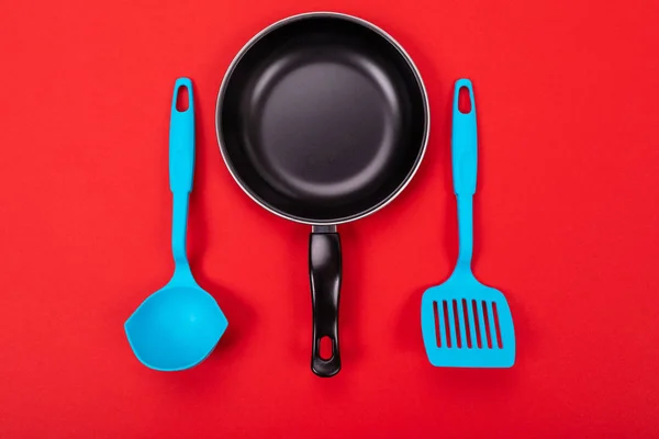 Ustensiles de cuisine pour cuisiner dans une cuisine isolée avec copyspace sur fond rouge — Photo