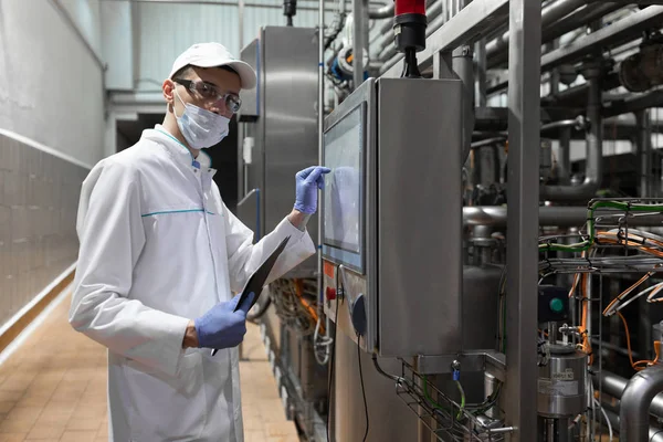 Tecnólogo tomar notas necessárias enquanto estiver em pé no departamento de produção de fábrica de laticínios — Fotografia de Stock