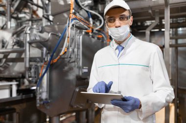 adam maske ve bornoz standları süt fabrikasında onun elinde bir tablet ile