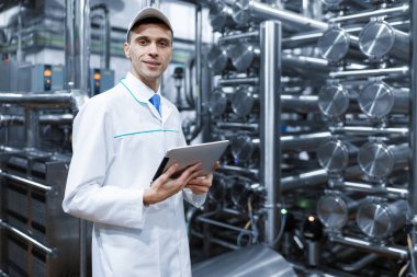 beyaz bir elbise içinde onun elinde bir tablet fabrikada üretim dükkanda adam
