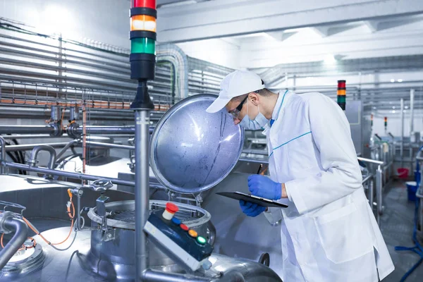 Teknikern kontrollerar produktionen av mejeriprodukter på anläggningen — Stockfoto