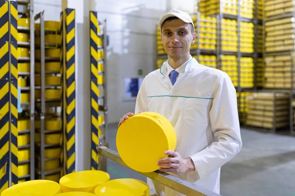 Hombre sosteniendo una cabeza de queso en una planta lechera —  Fotos de Stock