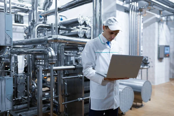 Tecnólogo com um laptop em suas mãos na fábrica de laticínios — Fotografia de Stock