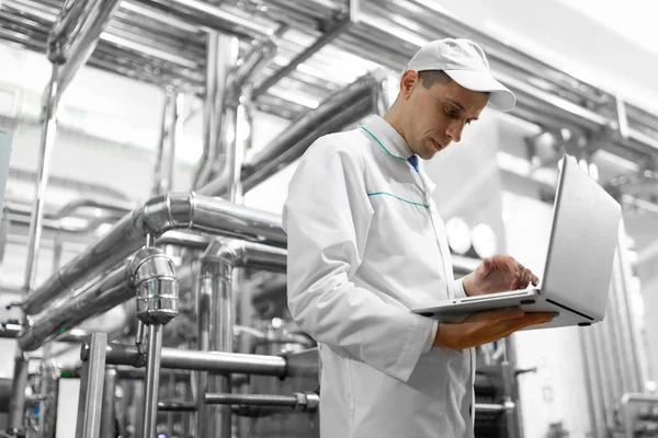 Tecnólogo con un portátil en sus manos en la planta láctea — Foto de Stock