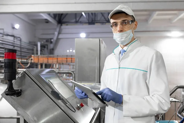 Technoloog staat met een tablet in de buurt van het digitale scherm aan de zuivel Plant — Stockfoto