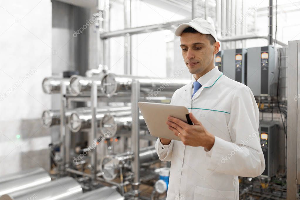 Technologist with a tablet in his hands at the dairy plant