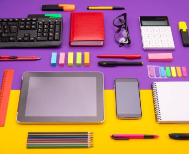 Tablet, hesap makinesi, Not defteri ve mor ve turuncu zemin üzerine smartphone ile modern çalışma yer. İş kavramı