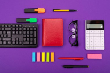 Klavye, notebook ve mor zemin üzerine gözlük ile modern çalışma alanı