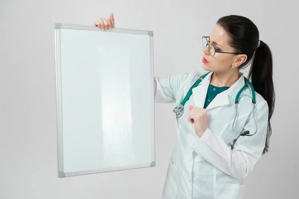 Porträt einer Frau mit Brille im weißen Gewand mit Magnettafel in den Händen isoliert auf weißem Hintergrund — Stockfoto