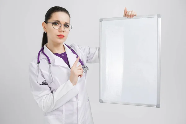 Retrato de mulher vestindo óculos em roupão branco com placa magnética em mãos isoladas sobre fundo branco — Fotografia de Stock