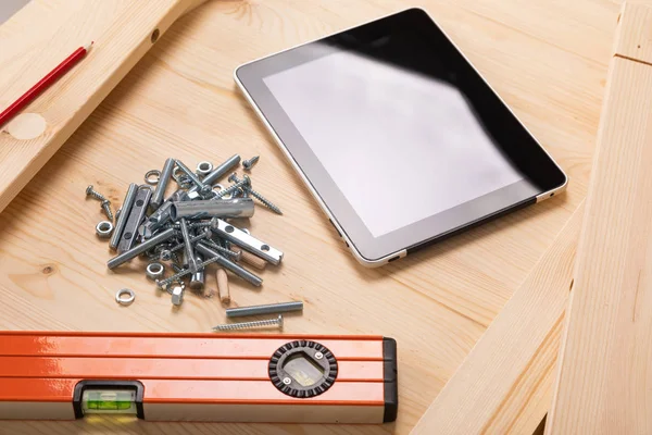 construction tool and a digital tablet lie on a light wooden table