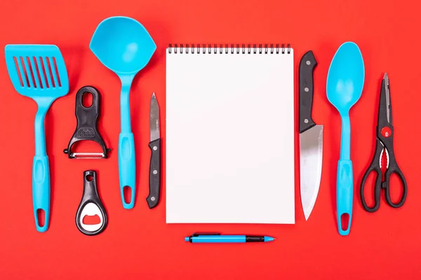 top view of a clean sheet and kitchen utensils next to it isolated on a red background