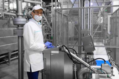 Süt fabrikasında üretim bölümü dururken gerekli notlar alarak teknoloji uzmanı