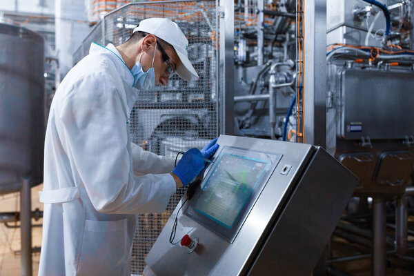 man in the mask and the robe works with the monitor to the Factory of dairy products