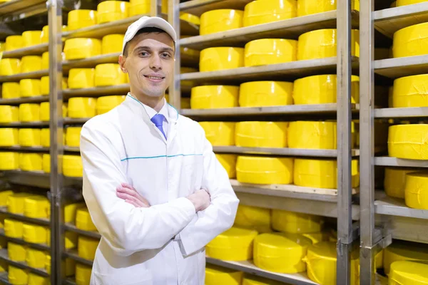 Muž stojí na pozadí stojanů sýra, mléka a mléčných výrobků v závodě — Stock fotografie