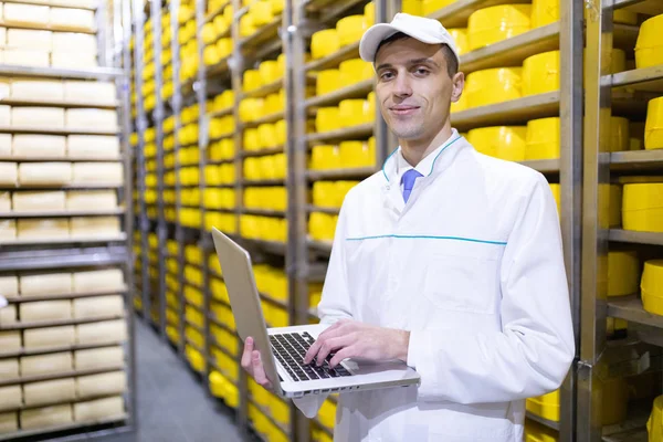 Trabajador con un portátil en sus manos en el almacén de queso —  Fotos de Stock