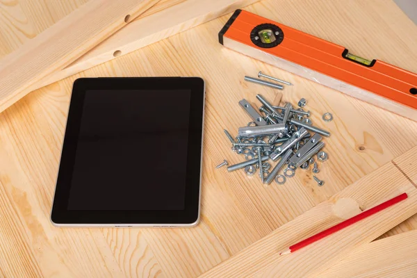 Ferramenta de construção e um tablet digital estão em uma mesa de madeira leve — Fotografia de Stock