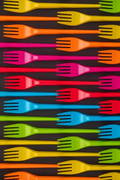 Many color plastic forks on a bright background