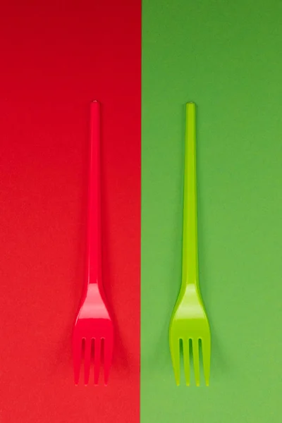 Par de garfos de plástico em vermelho e verde no topo do fundo — Fotografia de Stock