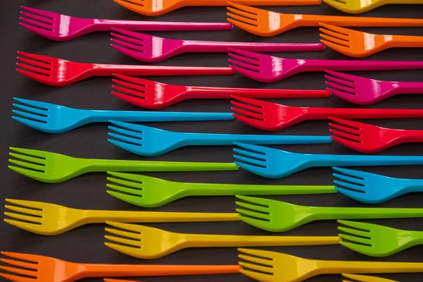 Many color plastic forks on a bright background