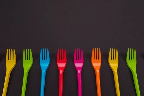 Many color plastic forks on a bright background