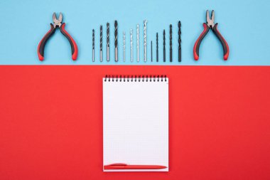 defter ve kalem renkli arka plan üzerinde ile metal işi araçlar kümesi
