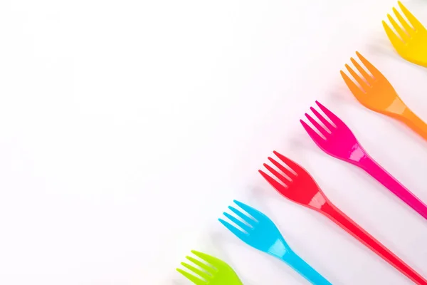 Muitos garfos de plástico de cor em um fundo brilhante — Fotografia de Stock