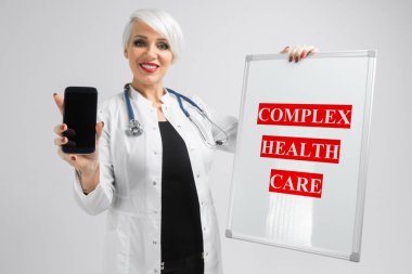 Portre sarışın kadın doktorlar kostüm manyetik kartı ile ve elleri üzerinde arka izole içinde smartphone