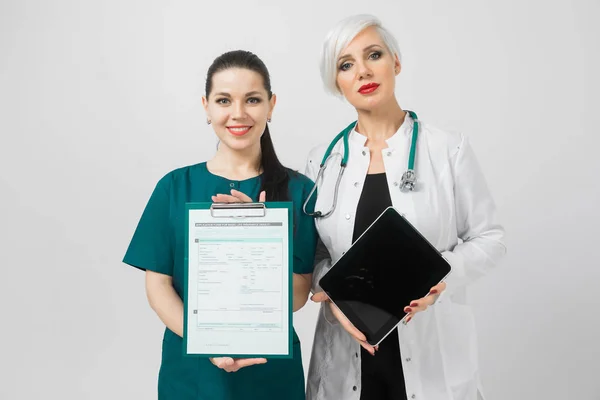 Retrato de duas mulheres jovens em trajes médicos isolados em segundo plano — Fotografia de Stock