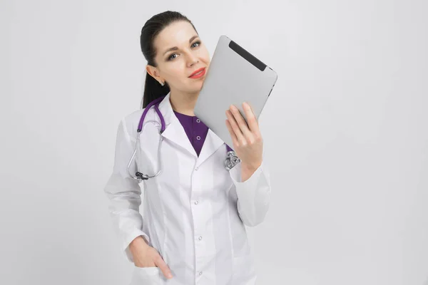 Retrato de morena em traje de médicos com um tablet moderno em suas mãos isolado no fundo — Fotografia de Stock