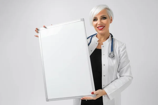 Elleri üzerinde arka izole manyetik bir yönetim kurulu ile doktorlar kostüm sarışın kadın portresi — Stok fotoğraf