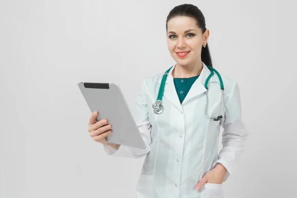 Retrato de morena em traje de médicos com um tablet moderno em suas mãos isolado no fundo — Fotografia de Stock