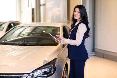 Arabanın yakınında duran ve bir tablet tutan şık sigorta ajanı