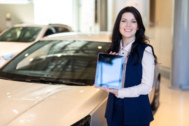 Arabanın yakınında duran ve bir tablet tutan şık sigorta ajanı